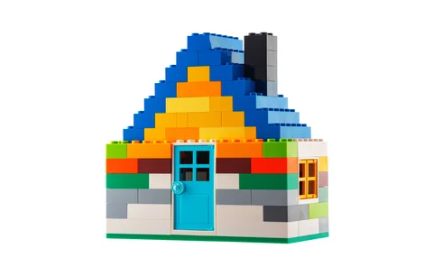 House made of classic building blocks, white studio background 