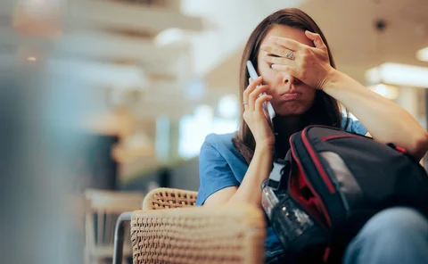  Woman Talking on the Phone Waiting in an Airport - stock photo Stressed traveler speaking on her cellphone feeling overwhelmed