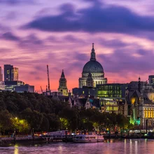 Golden light of sunrise illuminated the historic dome of St. Paul’s Cathedral and the futuristic spires of City skyscrapers overlooking the River Thames in the heart of London, UK.