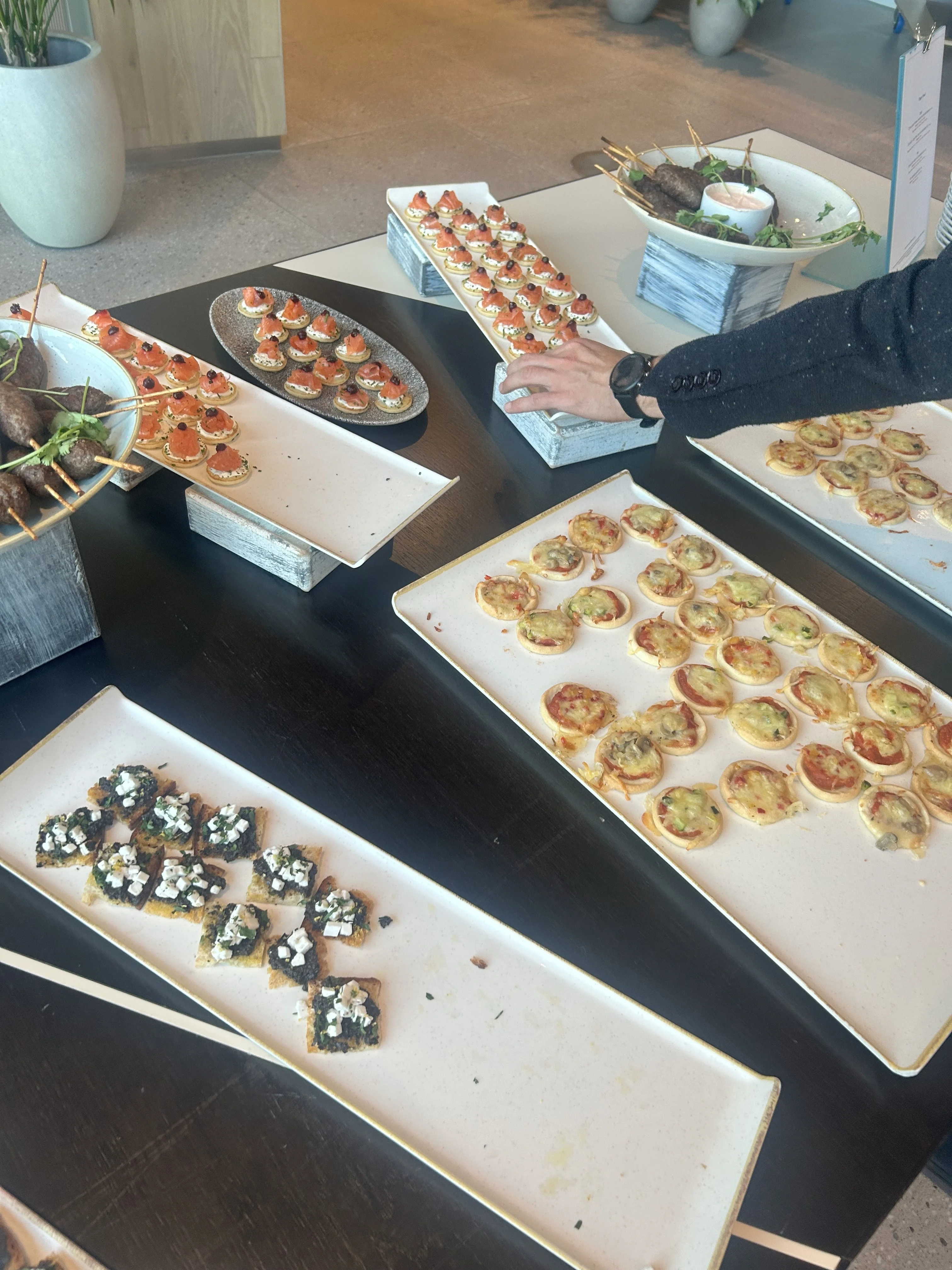 Table with the spread of canapes and a hand reaching for one